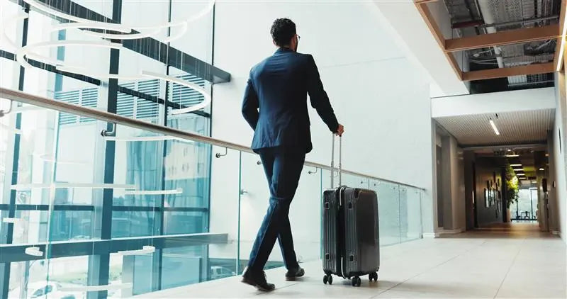 Man in a suit pulling a suitcase through an airport terminal