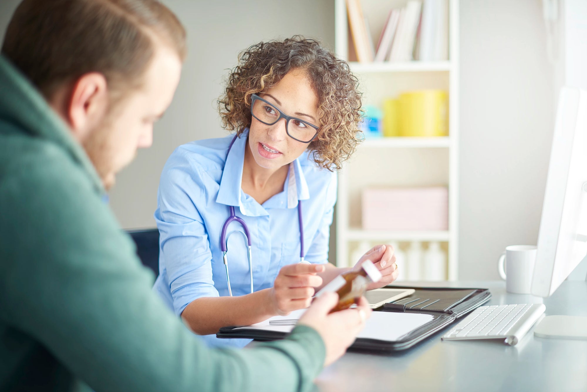 Doctor with stethoscope interacting with a patient in a medical office setting.