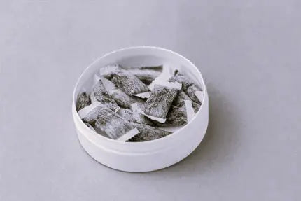 A tin of snus pouches in black and white colour