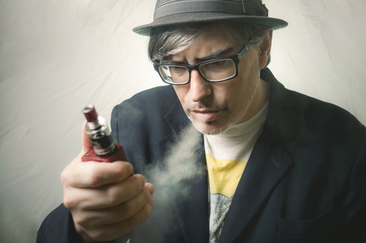 
Man looking at vape, while vaping