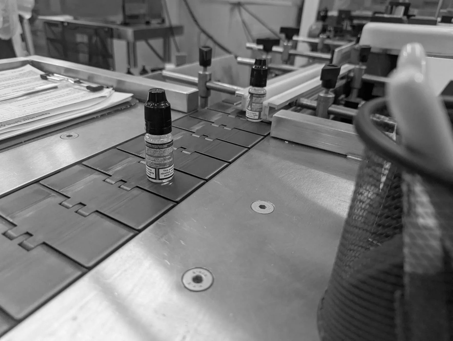 Black and white photo of e-liquid on a conveyor belt