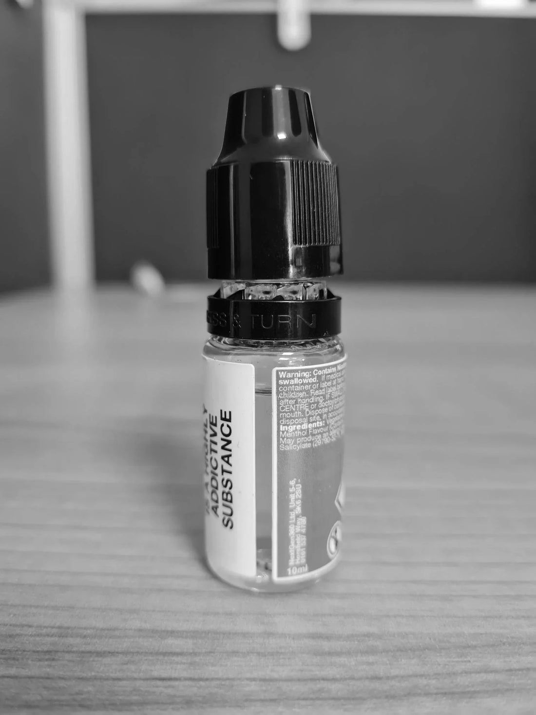 Small bottle with a black cap on a wooden surface