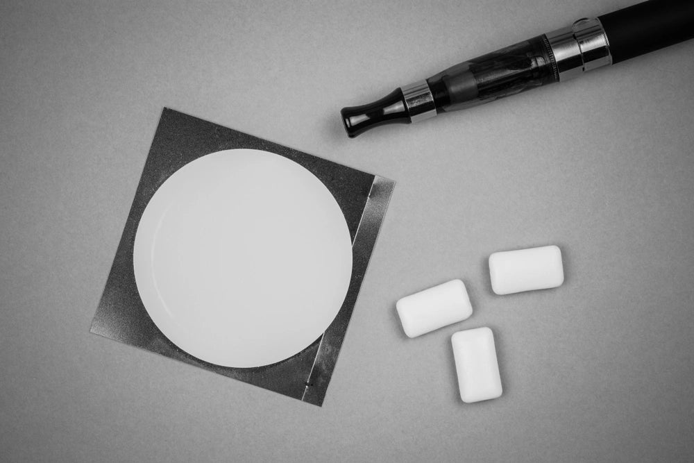 Vape kit and nicotine gum and packaging on a gray background